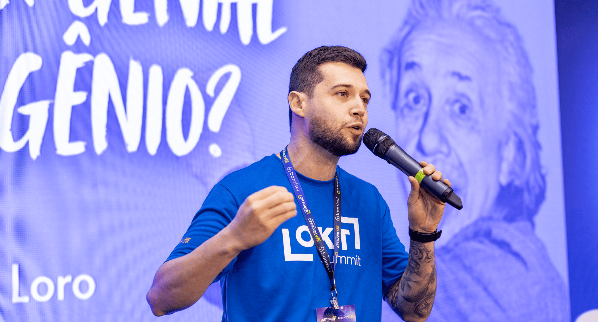 Imagem do palestrante com microfone na mão falando em público